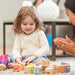 Child playing with alphabet blocks on the floor with an adult nearby