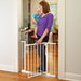 Woman holding a child next to a baby gate in a home setting